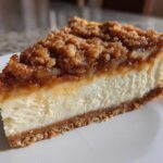 A perfect slice of amazing apple pie cheesecake featuring a creamy white layer, graham cracker crust, and a thick cinnamon apple crumble topping.