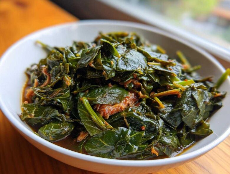 A close-up of tender, dark green collard greens simmered in a rich broth, served in a white bowl.