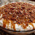 Close-up of a creamy Pecan Pie Dip topped generously with caramel sauce and chopped pecans.
