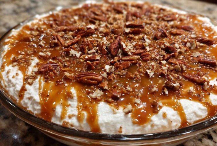 Close-up of a creamy Pecan Pie Dip topped generously with caramel sauce and chopped pecans.