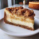 A perfect slice of apple pie cheesecake featuring a graham cracker crust, creamy filling, apple layer, and streusel topping.
