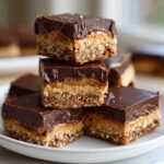 A stack of rich, layered Buckeye Graham Crackers bars featuring a graham cracker crust, peanut butter filling, and chocolate topping.