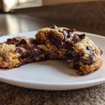 A chewy vegan chocolate chip cookie broken in half showing a gooey, melted chocolate center.