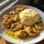 Plated chicken scampi in lemon butter sauce next to a mound of garlic parmesan rice.