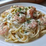 A close-up of creamy shrimp alfredo pasta, featuring pink shrimp tossed in rich white sauce and garnished with parsley.