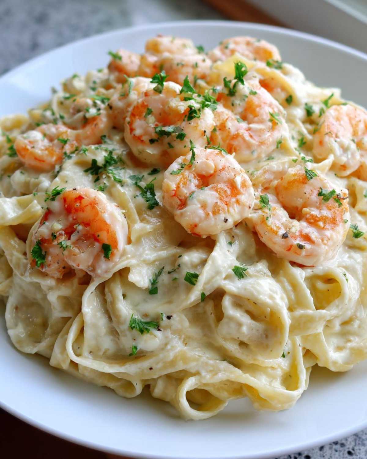 Close-up of creamy shrimp alfredo pasta topped with perfectly cooked shrimp and fresh parsley.