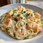 A close-up of creamy shrimp alfredo pasta topped with grated Parmesan cheese and fresh parsley.
