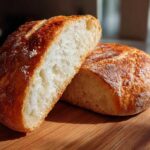 Close-up of a rustic loaf cut in half, showing the airy interior perfect for bread bowls.