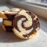 A stack of three delicious pinwheel cookies, with one cookie prominently displayed showing its beautiful chocolate and vanilla swirl pattern.