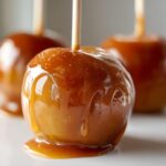 Close-up of a perfectly coated caramel apple with drips of thick caramel sauce, ready to eat.