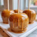 A close-up of one perfect caramel apple with thick caramel dripping down the sides, ready to eat.