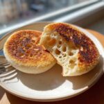 Close-up of a homemade English muffin split open, showing the signature nooks and crannies texture.