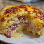 A close-up shot of a portion of homemade Reuben bake, showing melted cheese topping and chunks of corned beef inside.