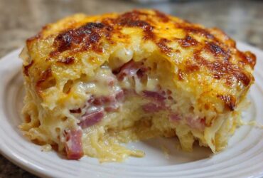 A close-up shot of a portion of homemade Reuben bake, showing melted cheese topping and chunks of corned beef inside.
