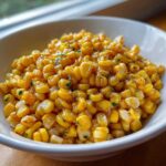 Close-up of sweet, glazed corn kernels coated in honey butter and garnished with parsley.