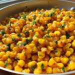 Close-up of golden, caramelized corn kernels tossed with honey butter and fresh parsley in a skillet.