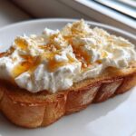 A thick slice of toasted bread topped generously with fluffy ricotta cheese, drizzled with honey and sprinkled with sugar for a perfect ricotta toast.