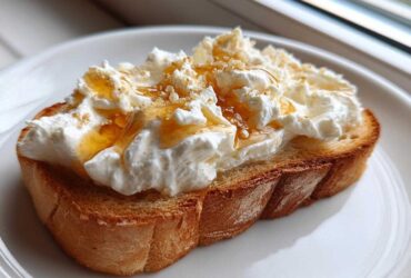 A thick slice of toasted bread topped generously with fluffy ricotta cheese, drizzled with honey and sprinkled with sugar for a perfect ricotta toast.