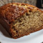 Close-up of a slice of moist banana bread showing its golden-brown, slightly glossy crust and tender crumb.
