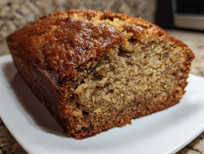 Close-up of a slice of moist banana bread showing its golden-brown, slightly glossy crust and tender crumb.