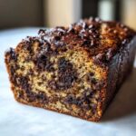 Close-up of a moist chocolate banana bread loaf with melted chocolate chips on top.
