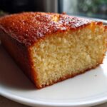 Close-up of a moist slice of golden brown condensed milk cake on a white plate.