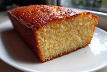 Close-up of a moist slice of golden brown condensed milk cake on a white plate.
