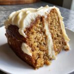 Close-up of a moist slice of spice cake layered and topped with thick cream cheese frosting.