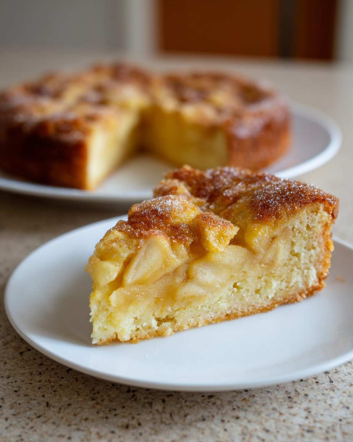 A close-up slice of moist Swedish apple cake showing tender cake base and baked apple filling, sprinkled with sugar.