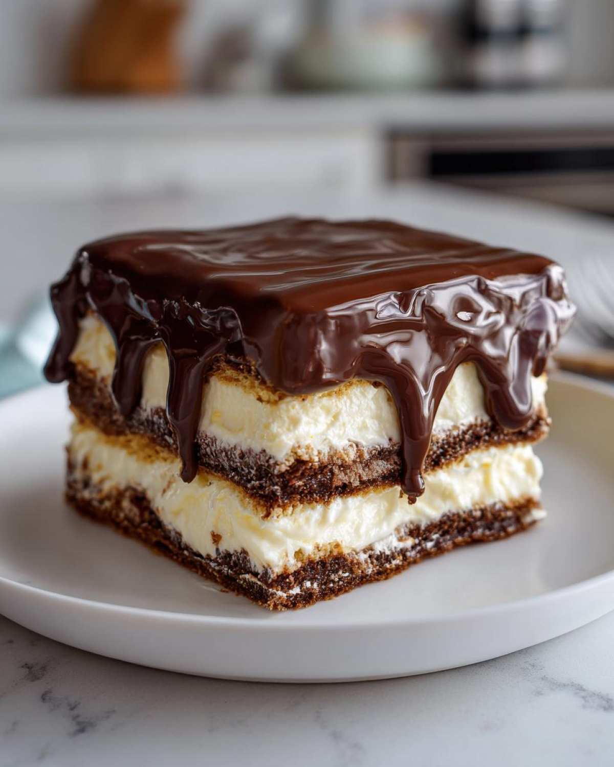 A square slice of no-bake chocolate eclair cake featuring layers of cream filling and chocolate glaze dripping down the sides.