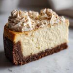 A close-up of a rich slice of eggnog cheesecake featuring a thick graham cracker crust and piped whipped cream dusted with nutmeg.