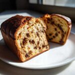 Cross-section of a loaf of soft raisin bread showing a rich, golden crumb packed with dark raisins.