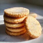 A stack of five round, golden sugar cookie rounds dusted heavily with sparkling sugar crystals.