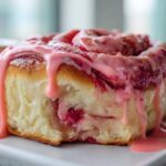 A single, fluffy Strawberry Cheesecake Sweet Rolls slice generously topped with dripping pink strawberry glaze.