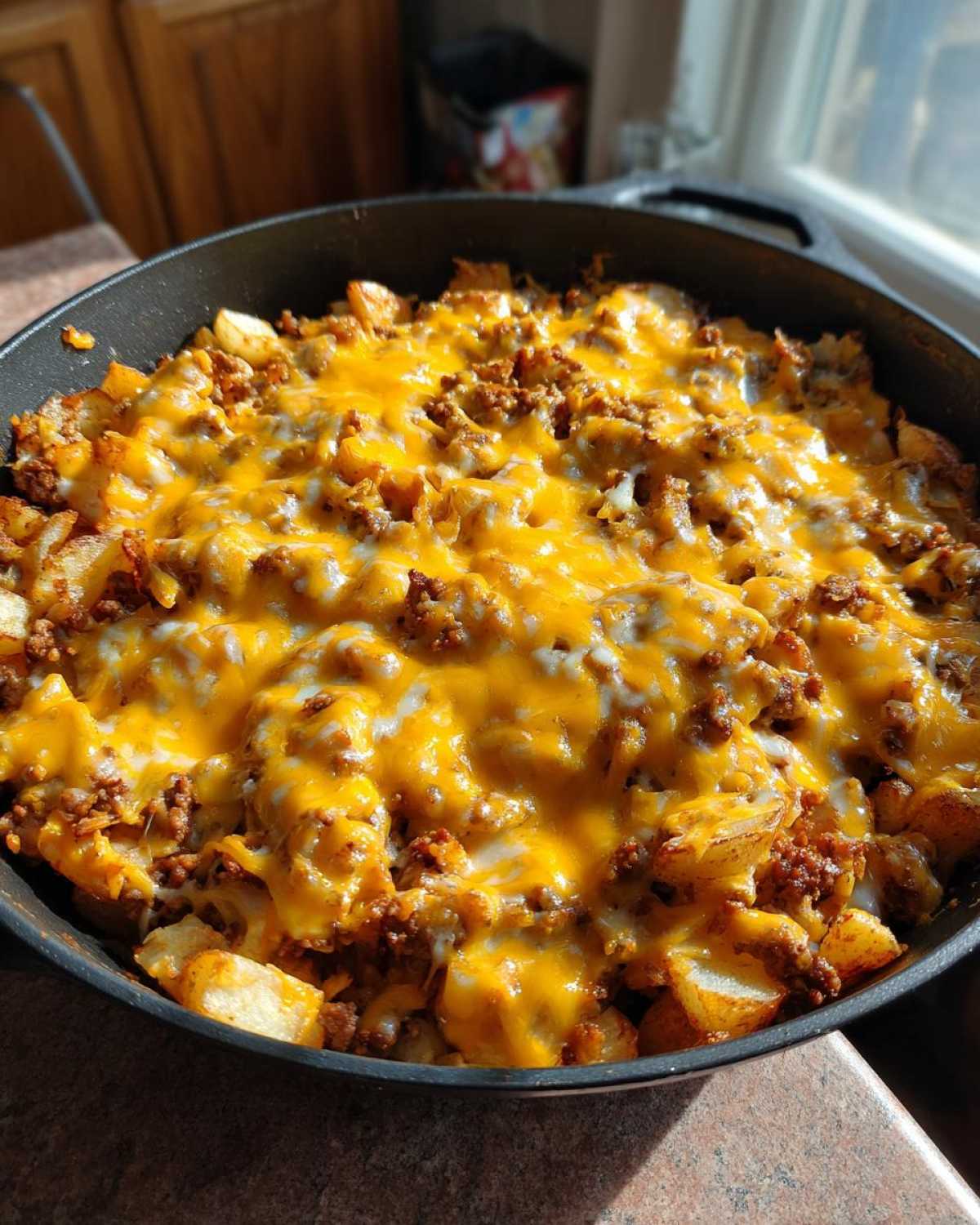 Close-up of Cheesy Taco Potatoes cooked in a black cast iron skillet, topped with melted cheddar cheese.