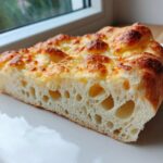Close-up of a thick slice showing the airy crumb structure of the amazing keto pizza crust with a golden, cheesy top.
