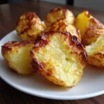 Close-up of several perfectly cooked roast potatoes showing a fluffy interior and deeply browned, crispy exterior.
