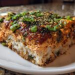A close-up, featured shot of a square slice of amazing sushi bake on a white plate.