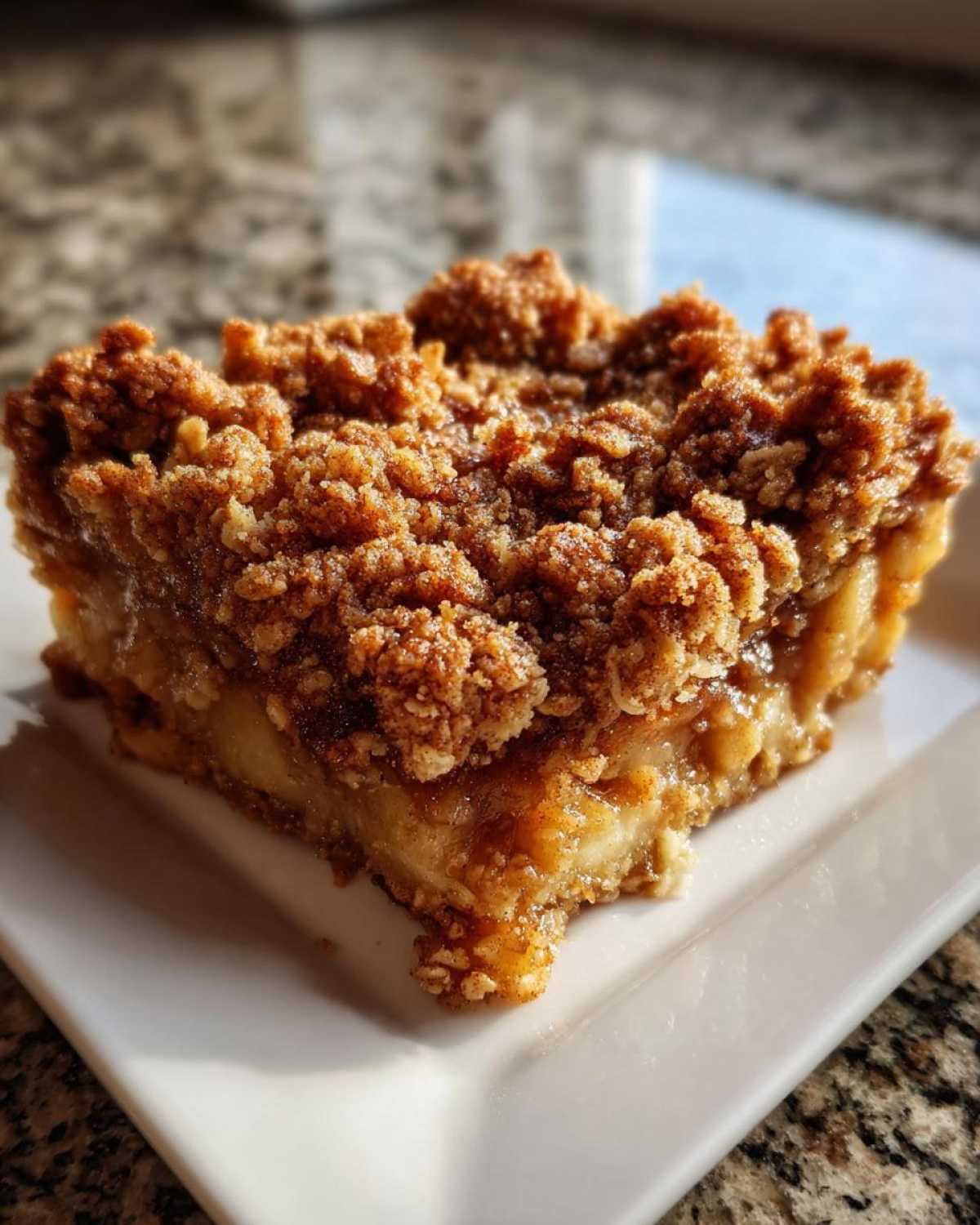 Close-up of a square serving of apple crisp recipe with thick, crumbly topping and soft apple filling.
