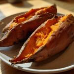 Two halves of fluffy baked sweet potatoes, split open and sprinkled with coarse salt, ready to eat.
