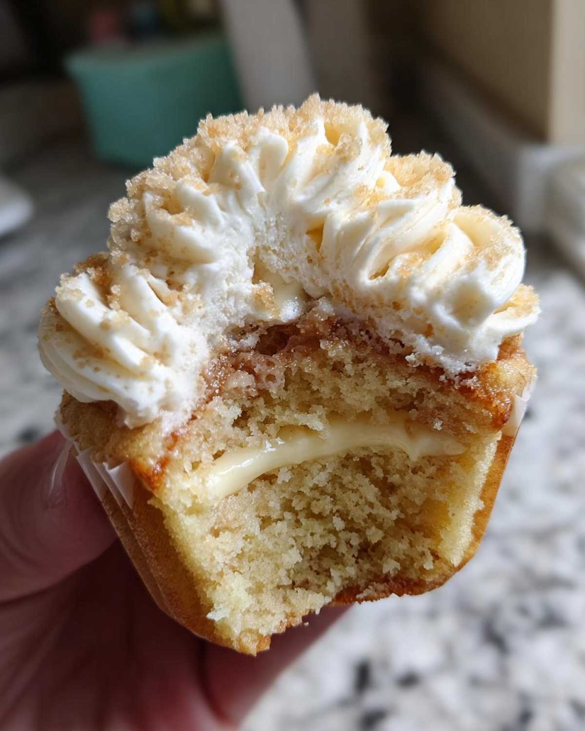 Close-up of a banana pudding cupcakes cut in half showing creamy filling, cake, and whipped topping.