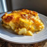A close-up serving of rich, cheesy potato casserole with a golden-brown, bubbly top.