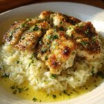 Golden seared chicken pieces served over creamy garlic parmesan rice, garnished with fresh parsley.