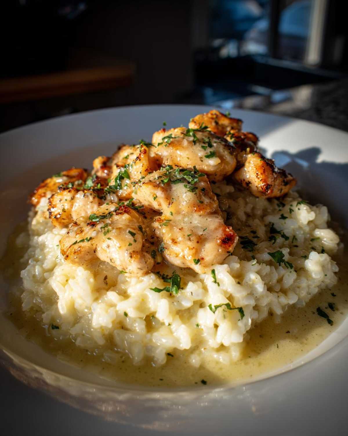 A close-up of chicken scampi pieces served over creamy garlic parmesan rice, garnished with parsley.