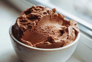 A close-up of rich, airy chocolate mousse scooped into a small, rustic white bowl.
