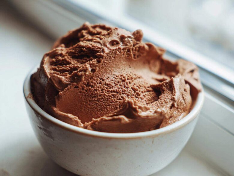 A close-up of rich, airy chocolate mousse scooped into a small, rustic white bowl.