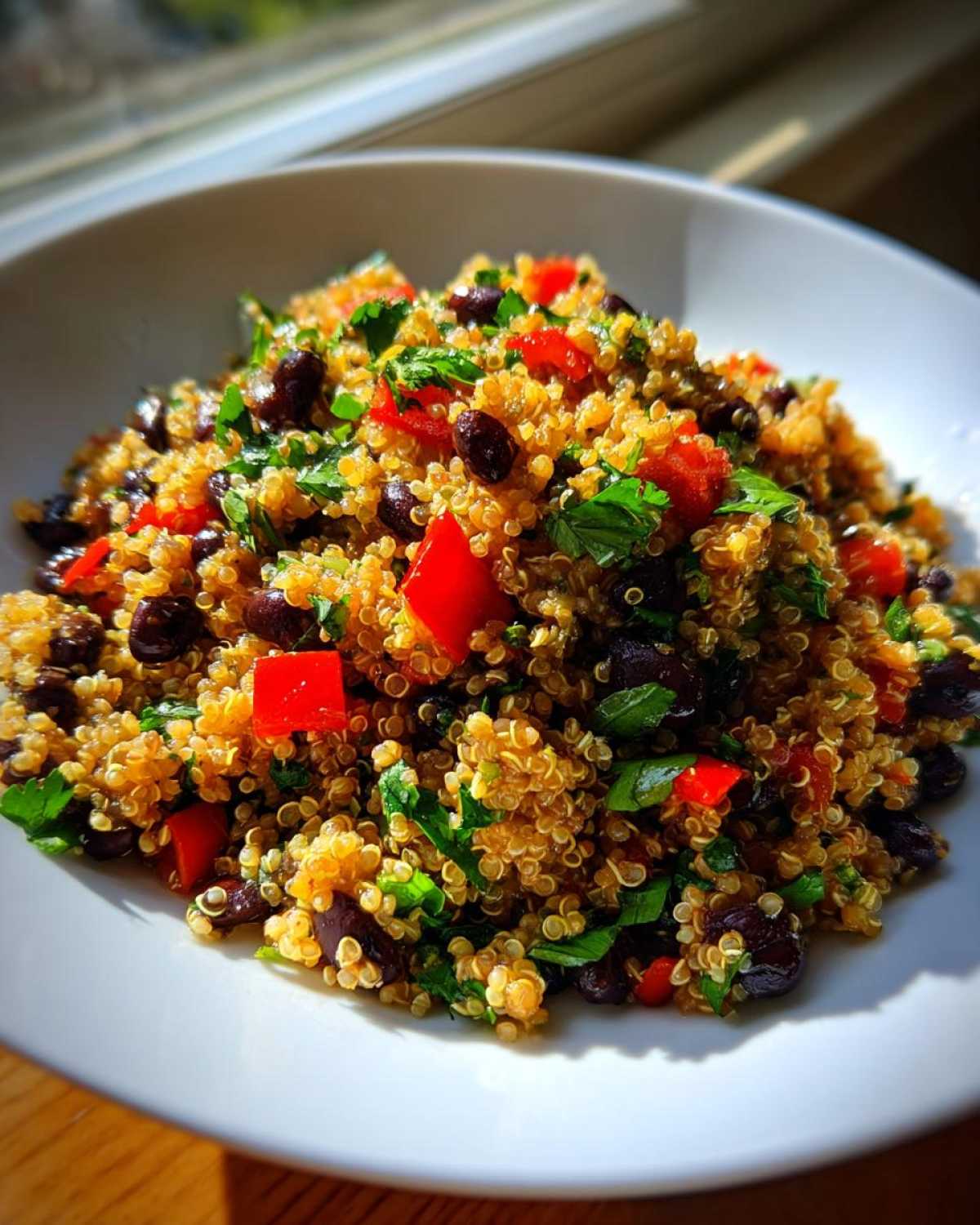 Close-up of a bright cilantro lime quinoa salad mixed with black beans and red bell peppers in a white bowl.