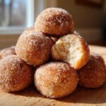 A stack of delicious cinnamon sugar snowball cookies, with one cookie broken open to show the soft interior.