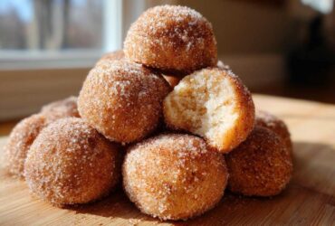 A stack of delicious cinnamon sugar snowball cookies, with one cookie broken open to show the soft interior.