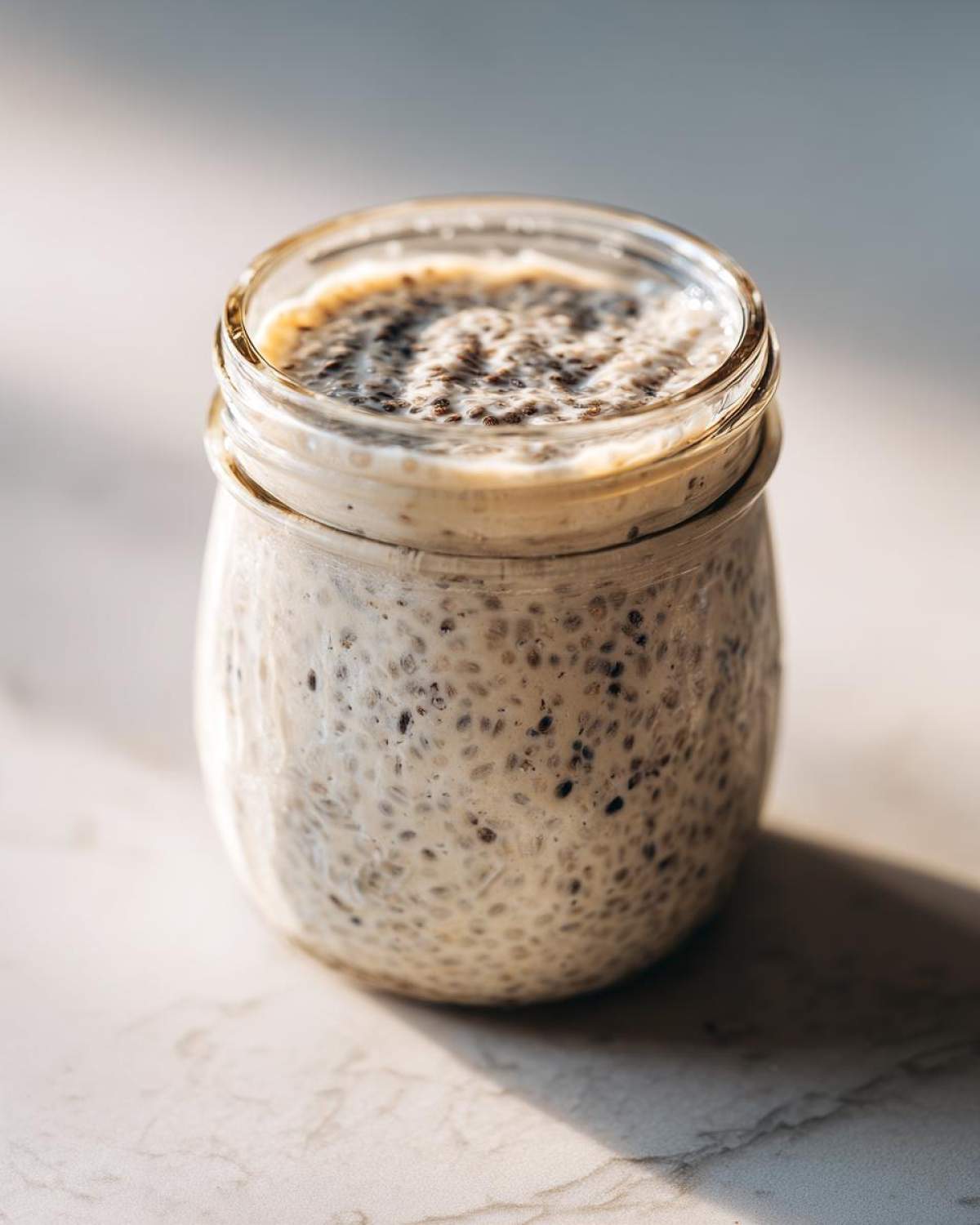 A glass jar filled with creamy, thick chia seed pudding, showing the texture of soaked chia seeds.